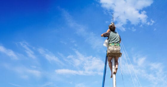 Person on a bosun's chair at the top of a mast - climbing the mast