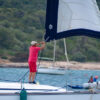 Man on a sailboat deck adjusting a furling sail