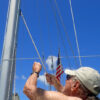 Man standing near sailboat mast - installing a new halyard