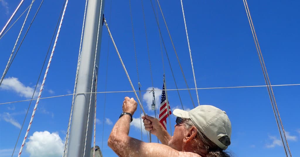 Man standing near sailboat mast - installing a new halyard