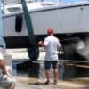 Man watches another main watching the bottom of a hauled out boat - hauling out your boat