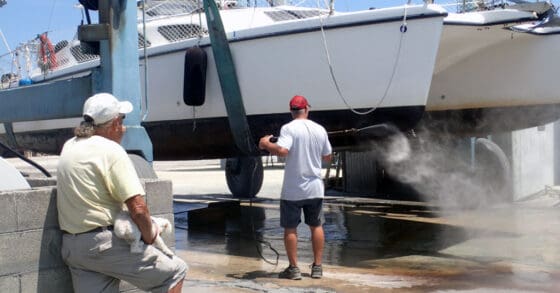 Man watches another main watching the bottom of a hauled out boat - hauling out your boat