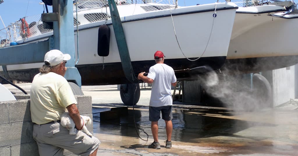 Man watches another main watching the bottom of a hauled out boat - hauling out your boat