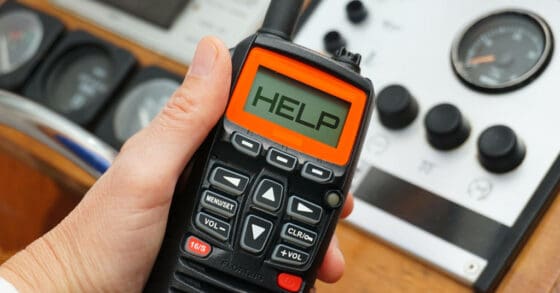 Person holding a radio with the word "help" on the display - getting help for a boat emergency