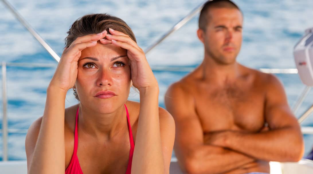 woman with hands on forehead in front of a man with arms crossed - reluctant cruiser