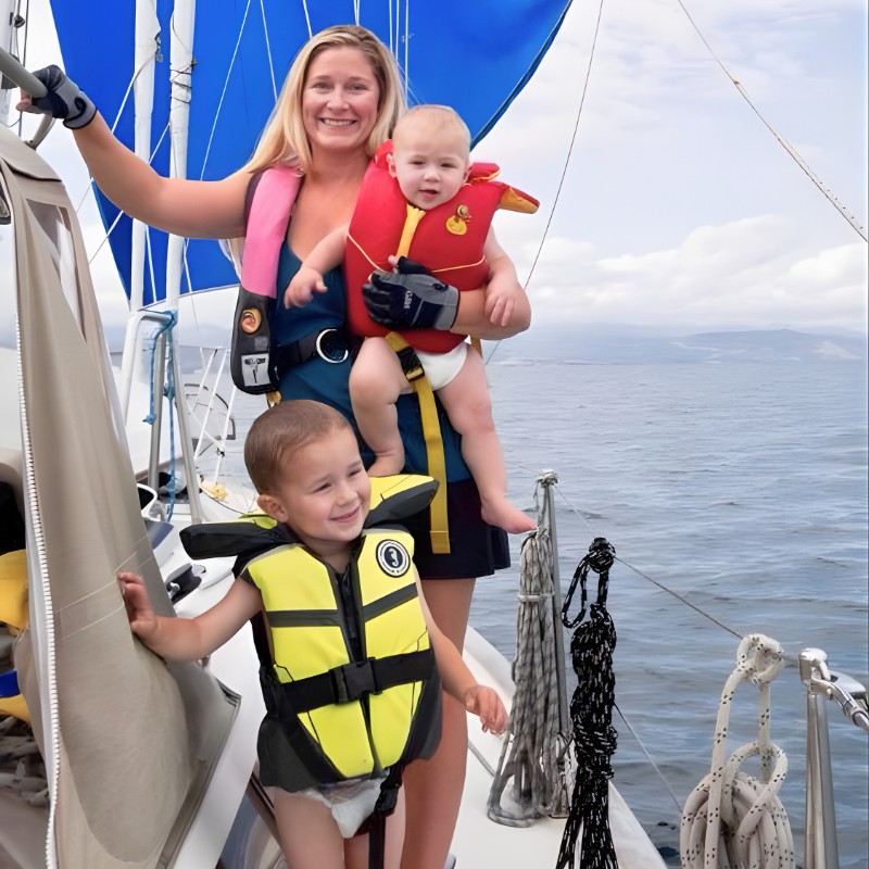 Woman sailor with baby and toddler on a sailboat