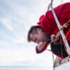 Man getting sick over the water from a sailboat - seasickness