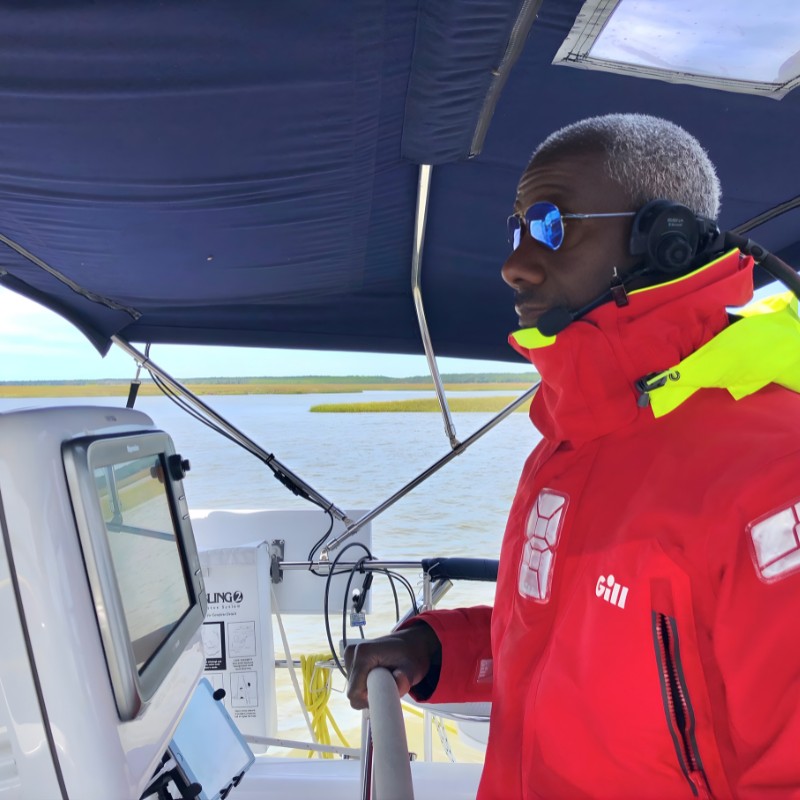 Man in foul weather jacket at the helm of a boat