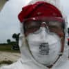 Person wearing white coveralls and a red hat with safety glasses and a dusk mask - dirty boat projects