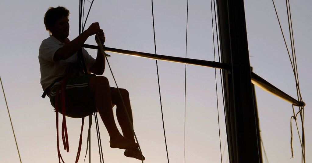 Silhouette of man repairing sailboat rigging - how to provision for a long passage
