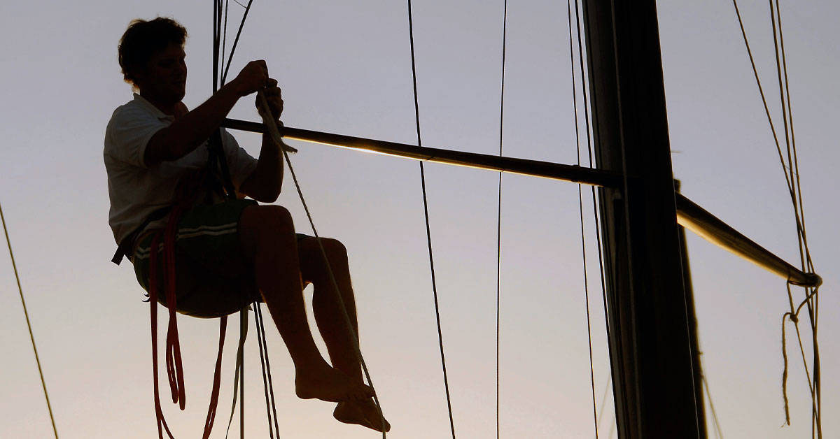 Silhouette of man repairing sailboat rigging - how to provision for a long passage