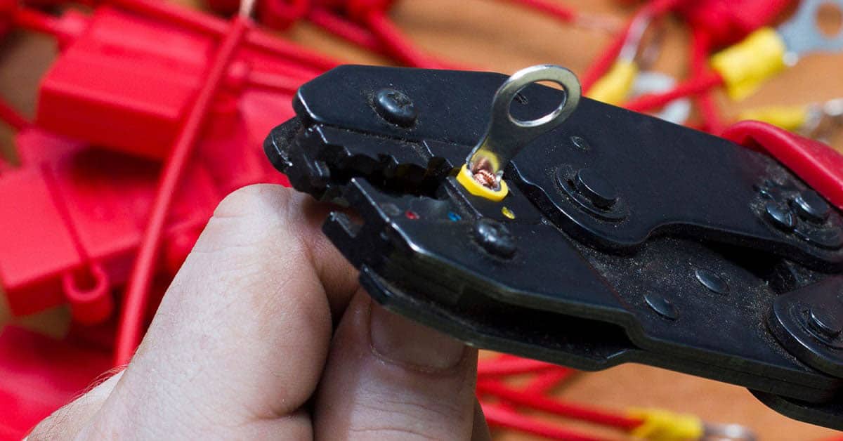 Hand holding a crimping tool and a wire - Tips for Boat Wiring