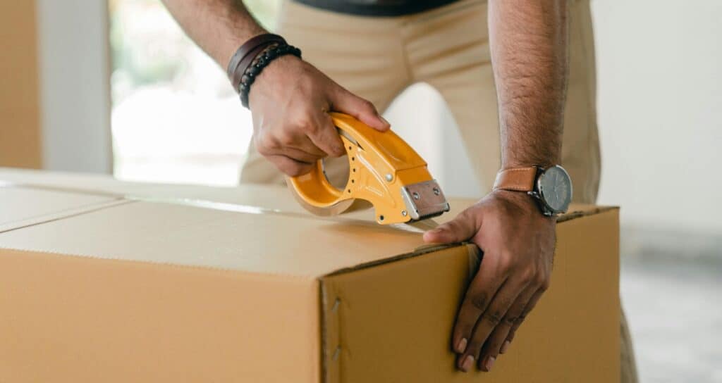 Sealing a cardboard moving box with tape while moving aboard a boat