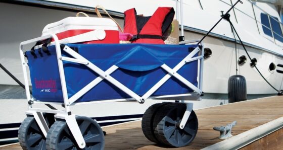 Collapsible wagon loaded with groceries and a cooler on a marina dock for boat provisioning