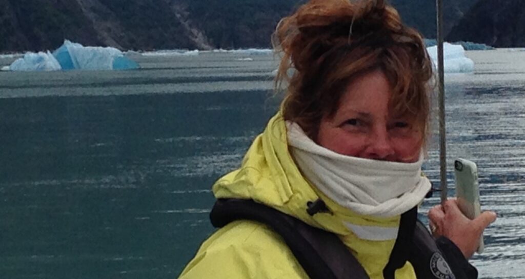 Sailor in yellow foul-weather gear on a sailboat in Alaska, cruising with rheumatoid arthritis