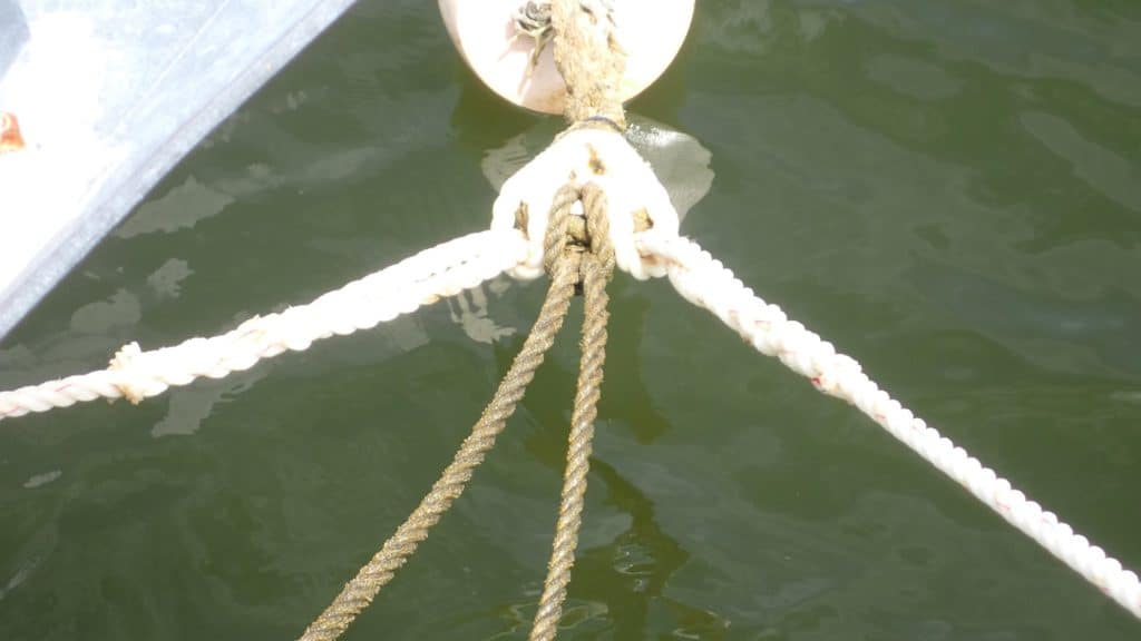 An anchor rope tied to a cleat securing a boat to the harbour