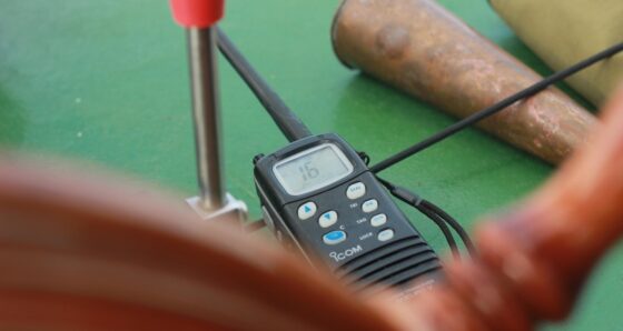 VHF radio next to a wooden ship's wheel