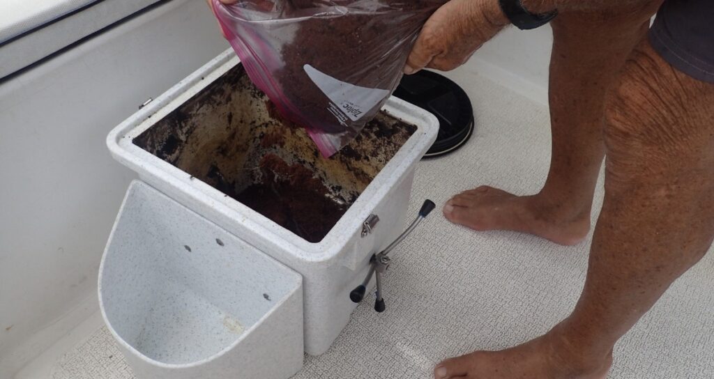 Person pouring prepared coconut coir into a Nature's Head composting toilet on a boat