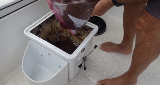 Person pouring prepared coconut coir into a Nature's Head composting toilet on a boat